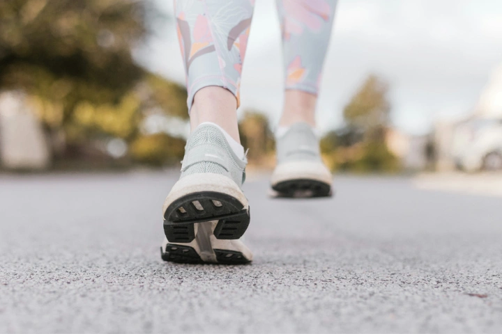 Detailní pohled na zdravou chůzi ve sportovních teniskách po cestě bez bolesti paty.